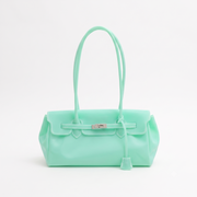 A mint green leather handbag with dual top handles, a front flap, and a silver-toned turn-lock closure, shown on a plain white studio background.